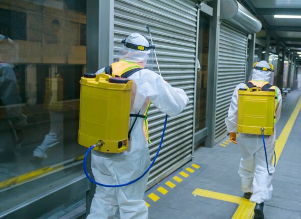 People wearing protective suits disinfecting public transport stations with chemicals to prevent the spread of the coronavirus